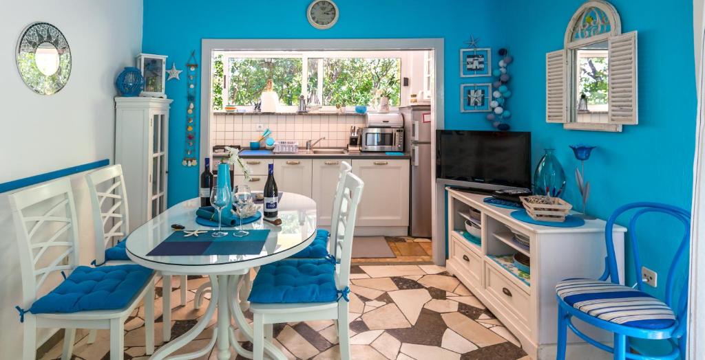 kuchnia z niebieskimi ścianami, stołem i krzesłami w obiekcie Holiday Home Jovis w Drveniku