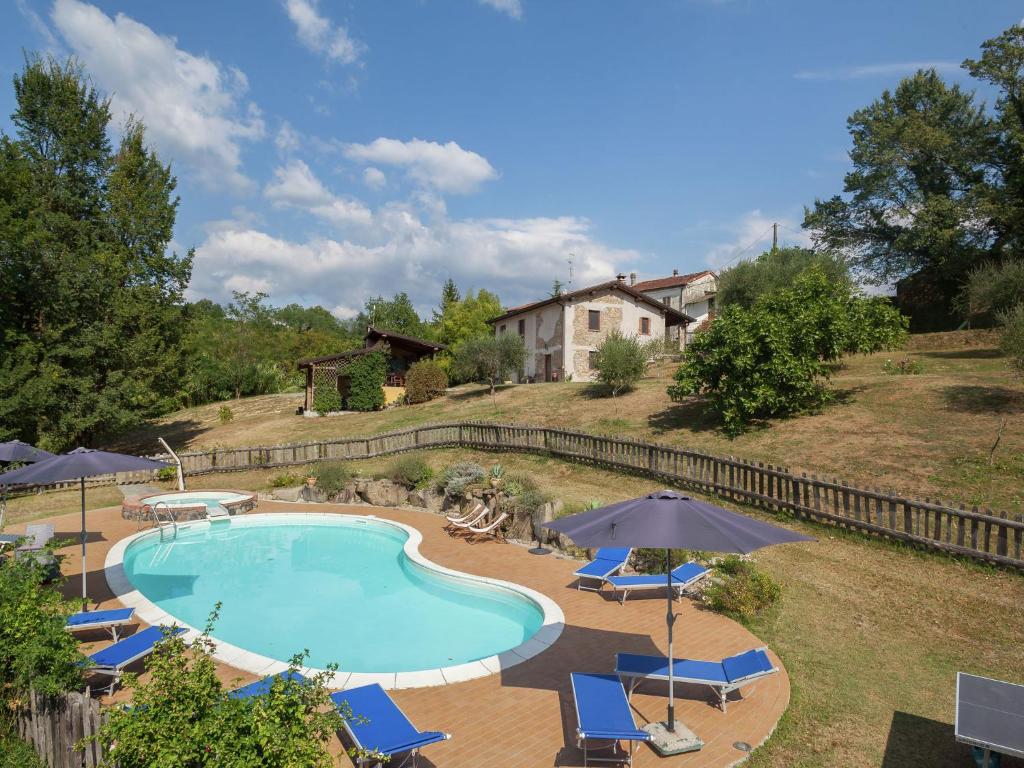 ein Pool mit Stühlen und Sonnenschirmen sowie ein Haus in der Unterkunft Belvilla by OYO Agriturismo Valle Fiorita in Aulla