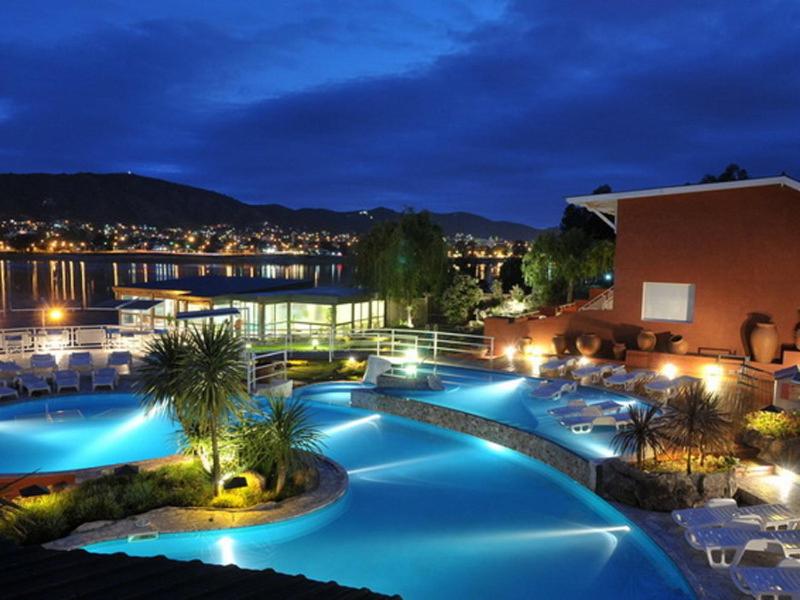 un complejo con piscinas azules y sillas por la noche en Lake Buenavista Apart Hotel & Suites en Villa Carlos Paz