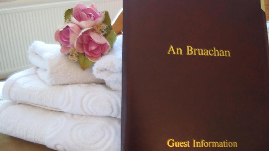 a book with a flower on top of towels at An Bruachan B&B in Kenmare