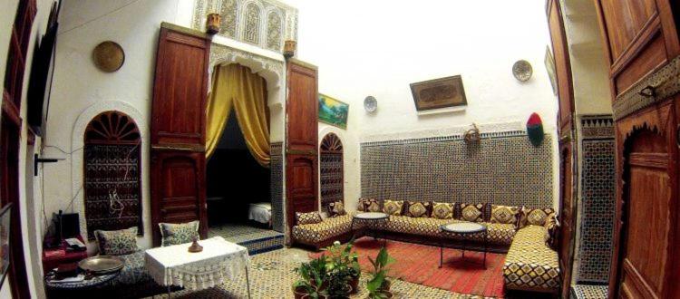 uma ampla sala de estar com um sofá e uma cadeira em Dar Ouassim em Fez