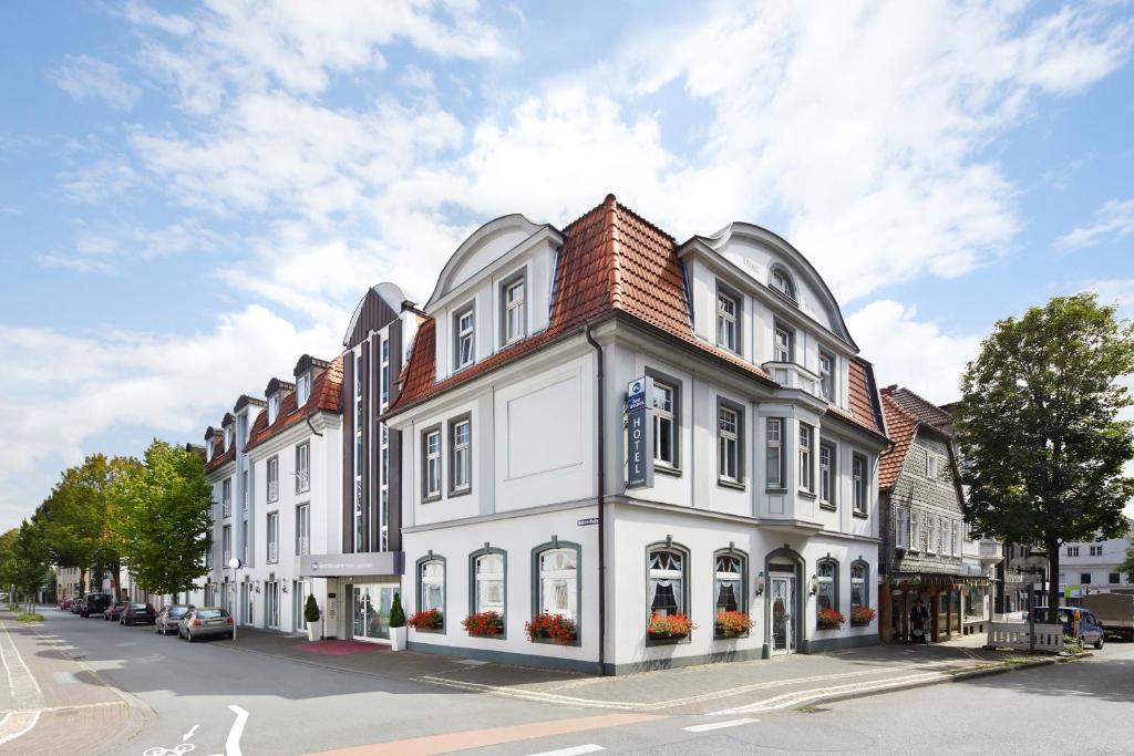 a white building with a red roof on a street at Best Western Hotel Lippstadt in Lippstadt