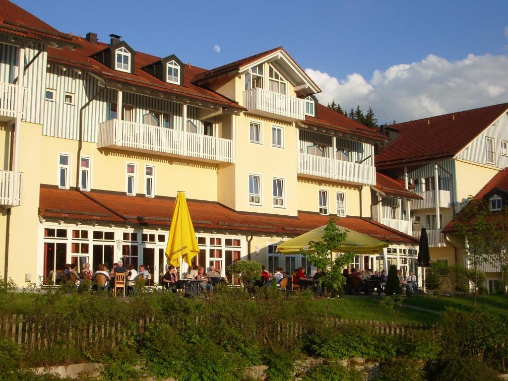 a large building with people sitting in front of it at Komforthotel Ahornhof in Lindberg