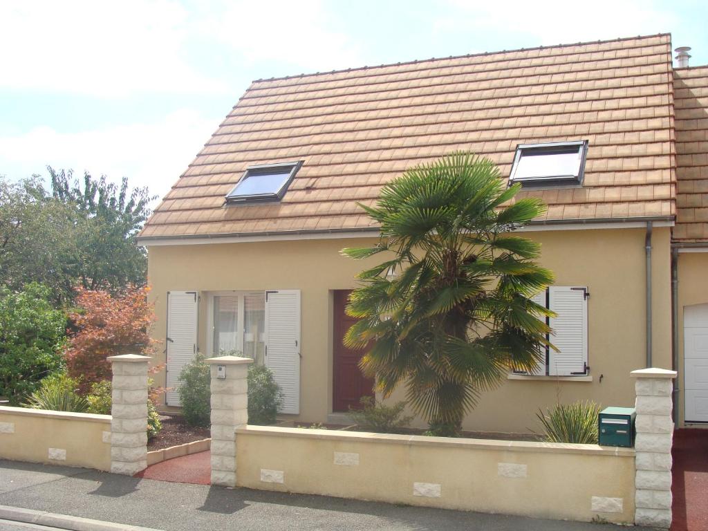 a house with a palm tree in front of it at Chambres d'hôtes Sébastien in Ruaudin