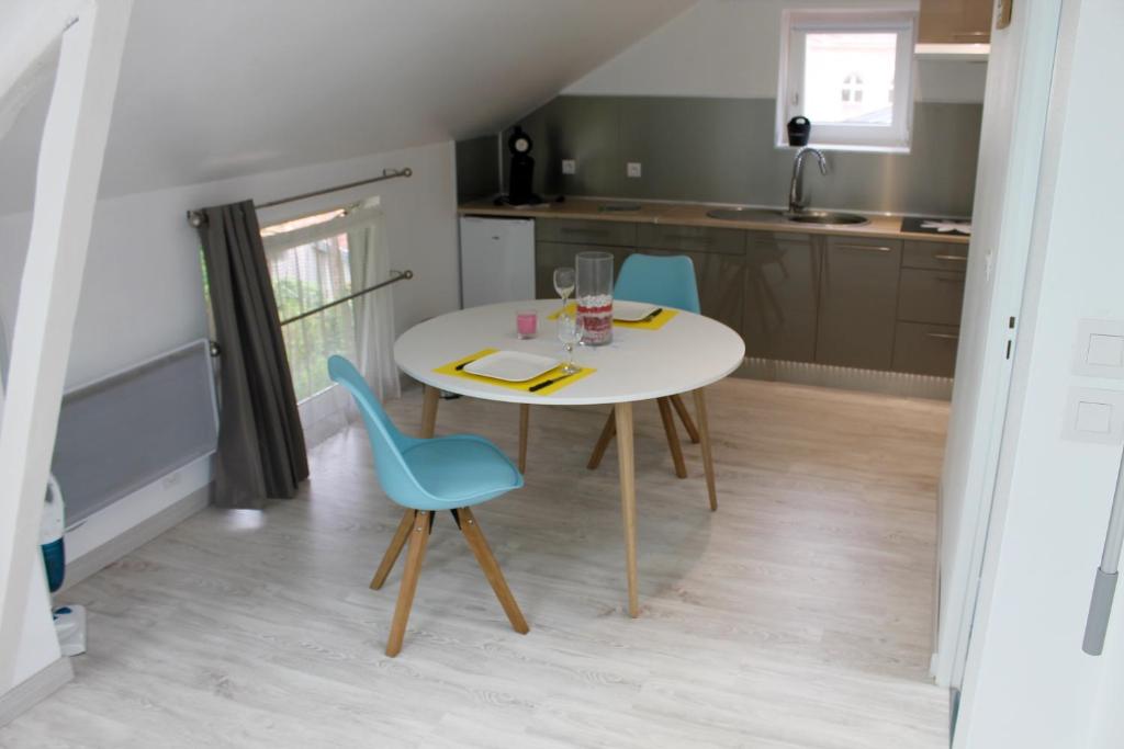 埃皮納勒的住宿－Gîte LE JARDINIER，厨房配有白色的桌子和2把蓝色的椅子