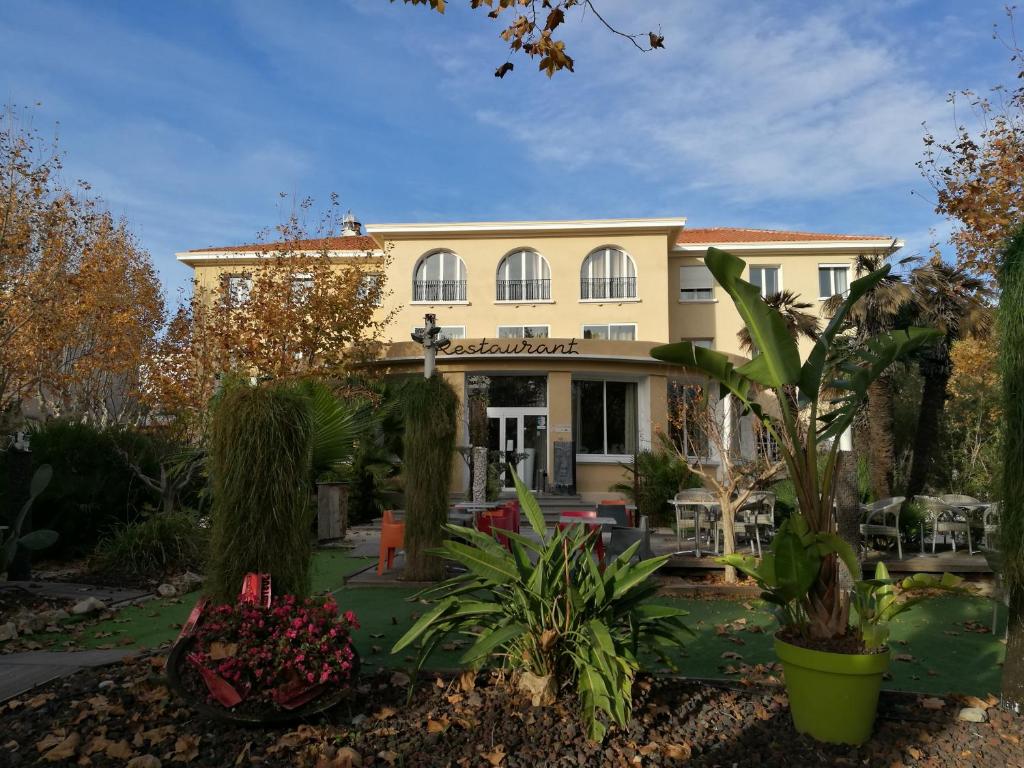 una casa grande con plantas delante en Adonis Sanary Grand Hôtel des Bains en Sanary-sur-Mer