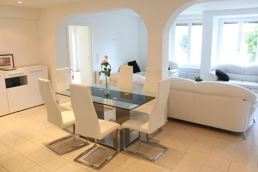 une salle à manger avec une table en verre et des chaises blanches dans l'établissement Ferienwohnung Amperblick Fürstenfeldbruck, à Fürstenfeldbruck