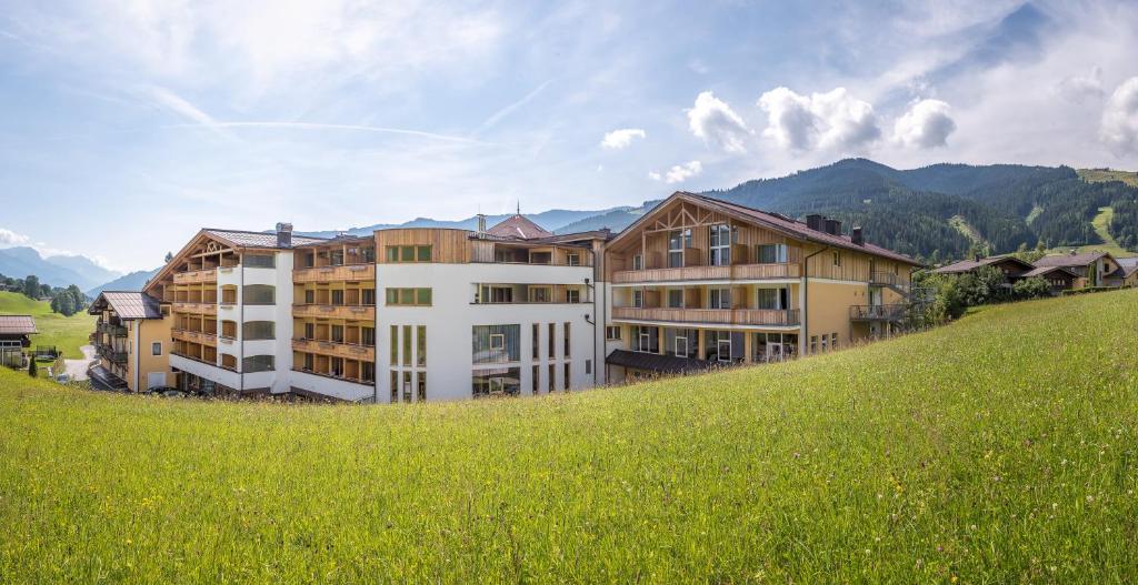 un grand bâtiment sur une colline avec un champ verdoyant dans l'établissement Hotel Leonhard, à Leogang