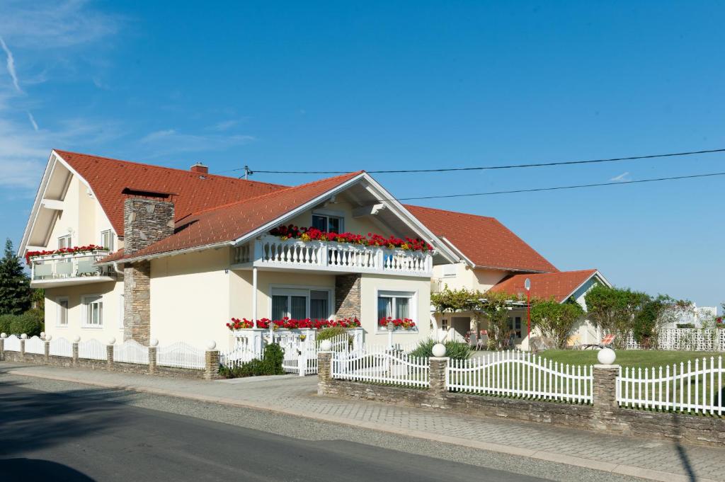 a white house with a red roof and a white fence at Appartement Schober in Kukmirn