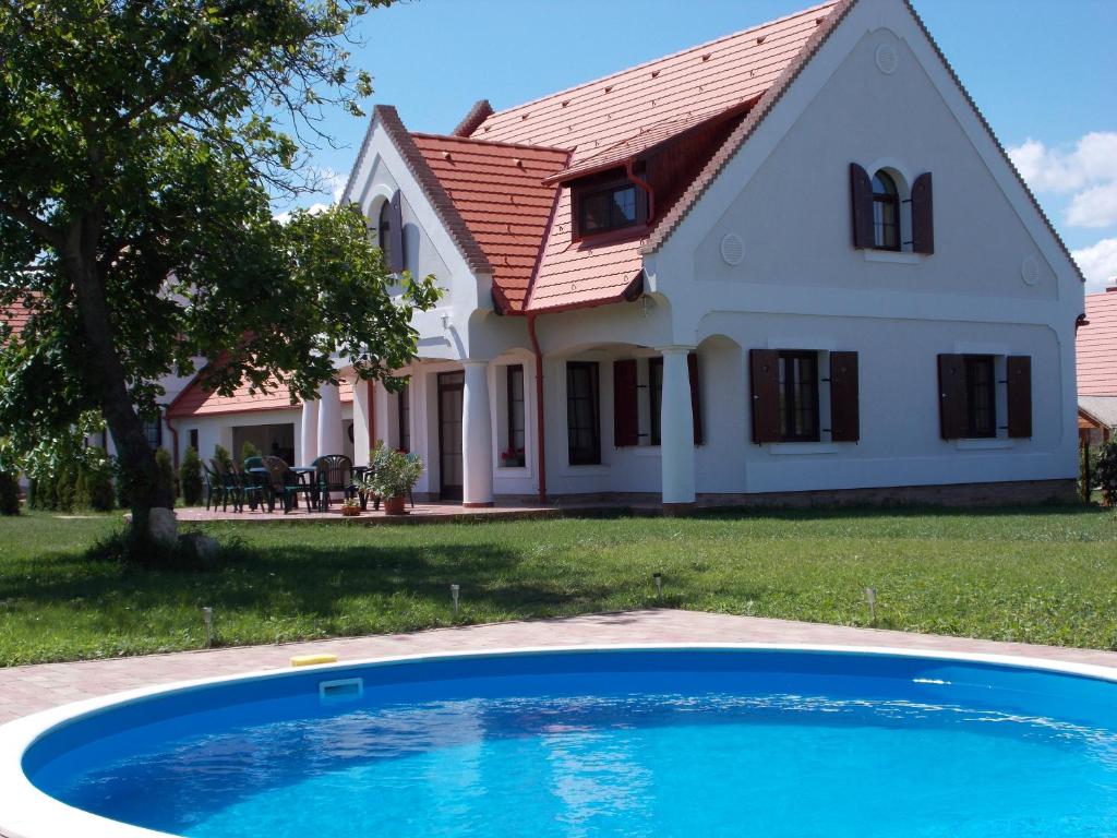 una casa con una piscina azul delante de ella en Hétkanyar Vendégház en Nagyvázsony