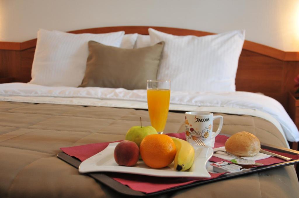 een dienblad met fruit en een glas sinaasappelsap op een bed bij Hotel Terex in Sarajevo