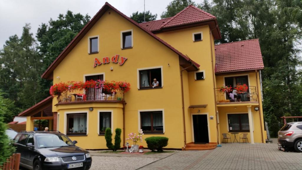 a yellow house with a dog in a window at Dom Goscinny Andy in Pobierowo