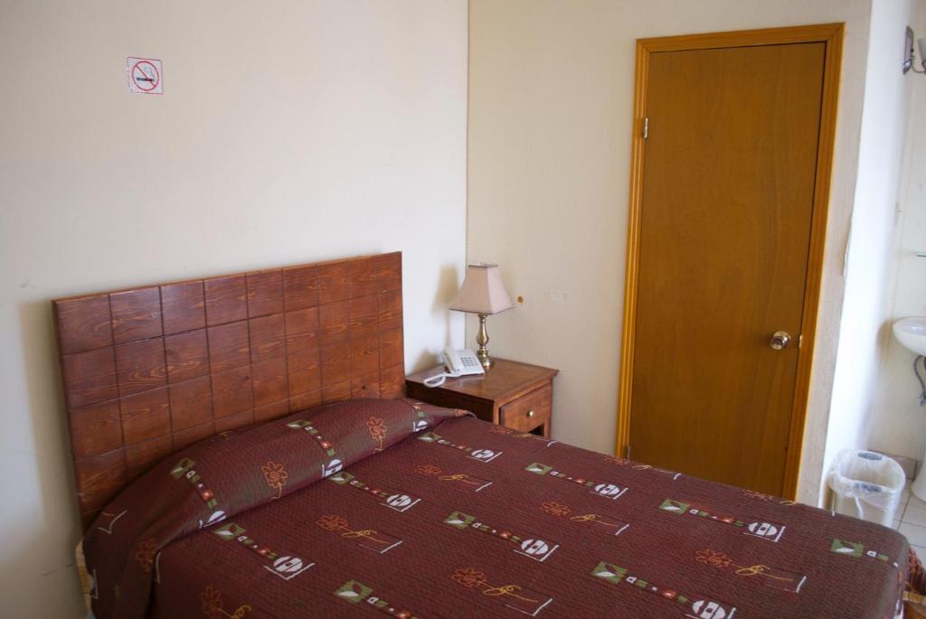 a bedroom with a bed and a wooden head board at Hotel Centric Chihuahua in Chihuahua