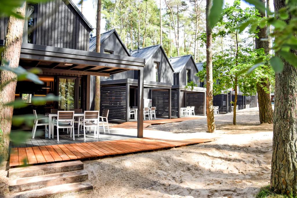 a house in the woods with a wooden deck at Baltic Lodge in Pobierowo