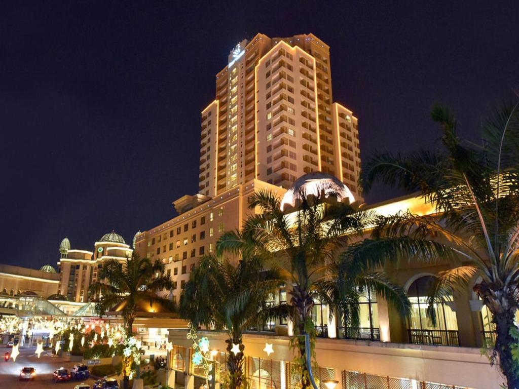 um grande edifício com palmeiras em frente em Raintree Resort Suites em Petaling Jaya