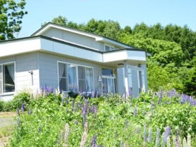 a house with a field of flowers in front of it at Abashiri Ryuhyou no Oka guesthouse in Abashiri