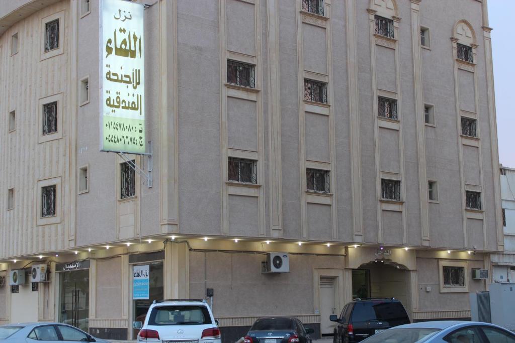 un gran edificio con coches estacionados frente a él en Nozul Al Leqa Apartments, en Al Kharj