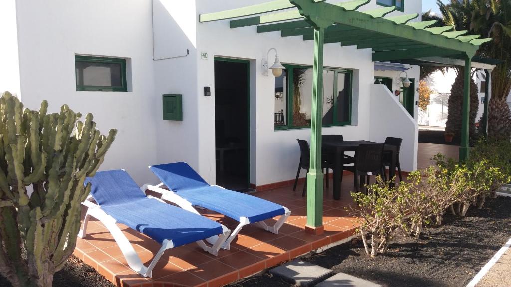 a patio with blue chairs and a house with a cactus at Bungalow Franck in Puerto del Carmen