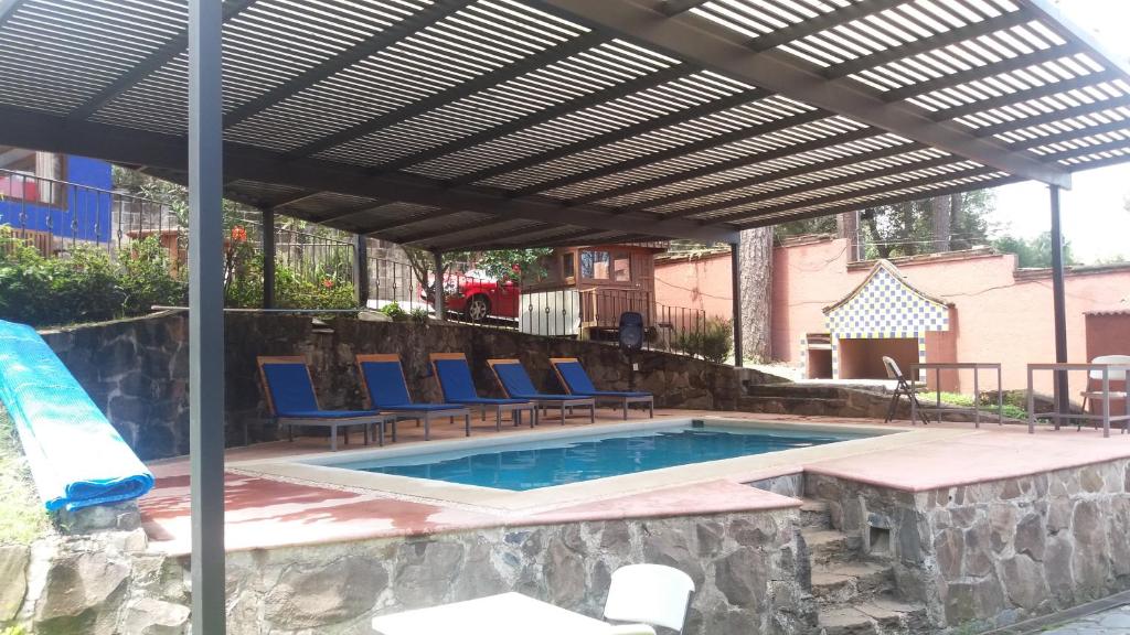 une piscine avec des chaises bleues et une pergola en bois dans l'établissement Hotel Casa Valle, à Valle de Bravo