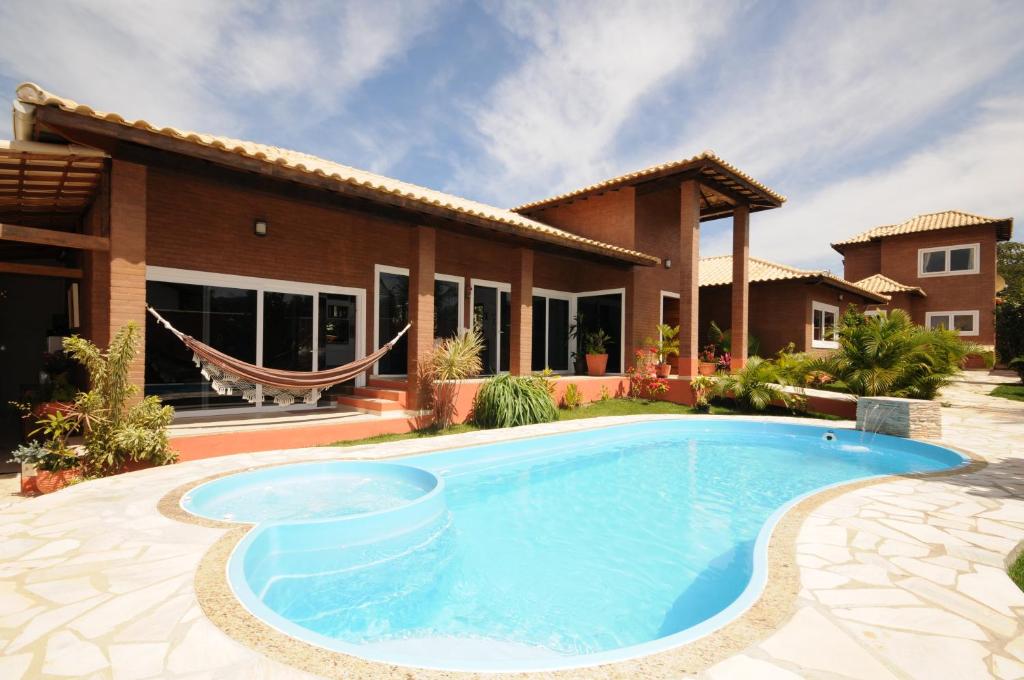 eine Villa mit einem Pool vor einem Haus in der Unterkunft Ecco House Buzios in Búzios