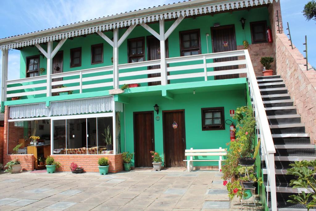 um edifício verde com uma escada em frente em Pousada Manu em Canela