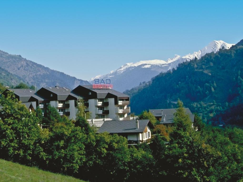 a hotel on a hill with mountains in the background at Badehotel Salina Maris – Wellness & Vintage in Mörel