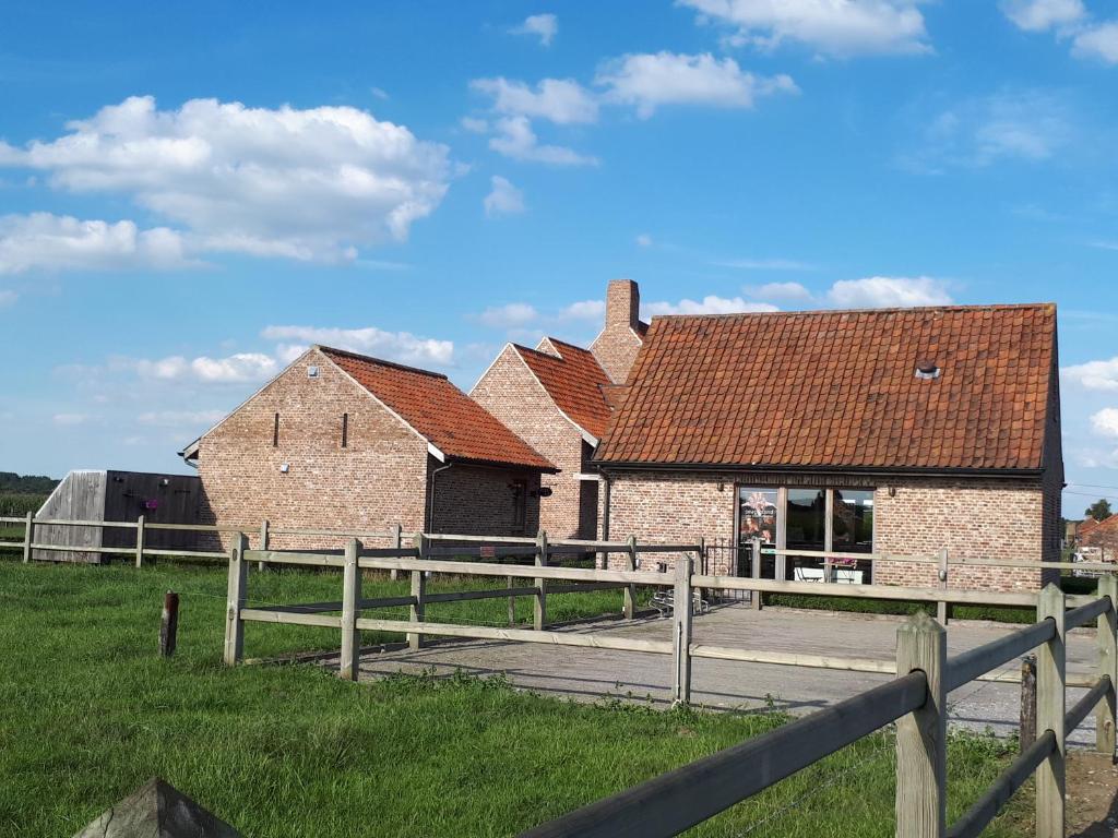 un viejo edificio de ladrillo con una valla en un campo en B&B 't Hoveke, en Wingene