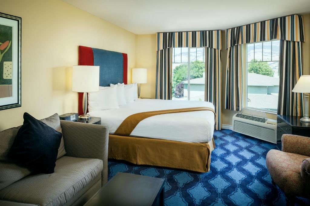 a hotel room with a bed and a couch at Plaza Inn & Suites at Ashland Creek in Ashland