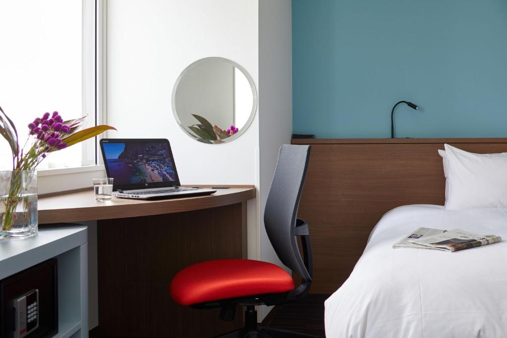 a hotel room with a bed and a desk with a laptop at the b shimbashi toranomon in Tokyo