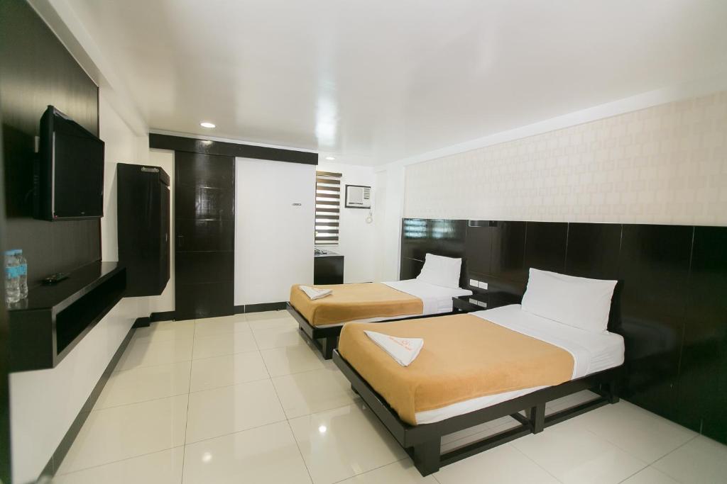 a hotel room with two beds and a television at Sun Garden Hotel Tarlac in Tarlac