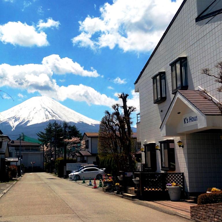 een met sneeuw bedekte berg in de verte achter een gebouw bij K's House Fuji View - Travelers Hostel in Fujikawaguchiko