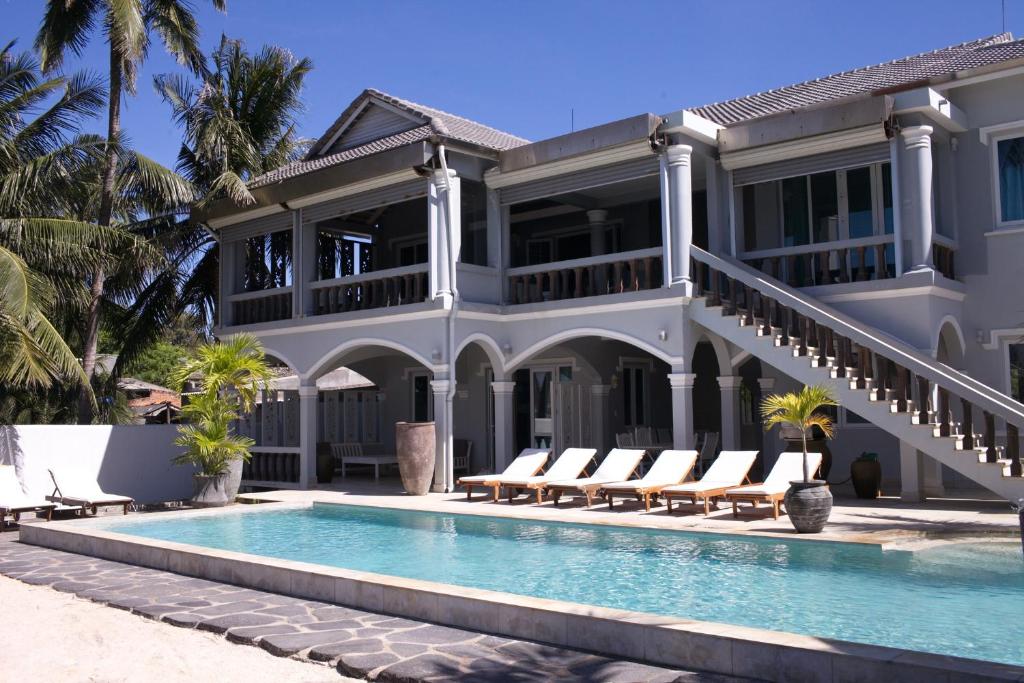 a villa with a swimming pool in front of a house at The Boathouse vietnam in Mui Ne