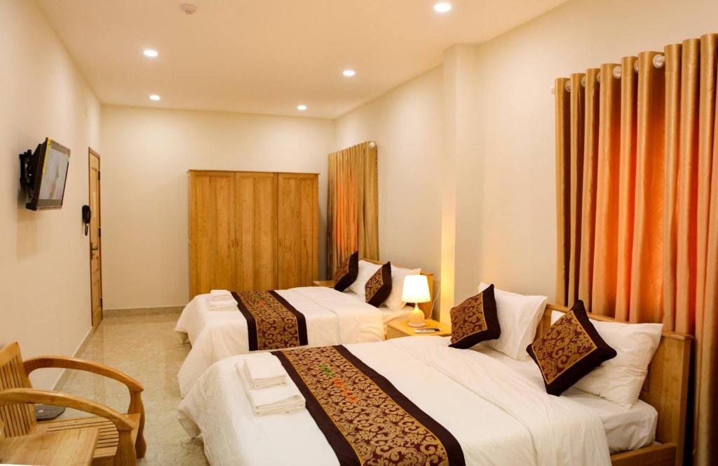 a hotel room with two beds and a chair at Minh Manh Hotel in Pleiku