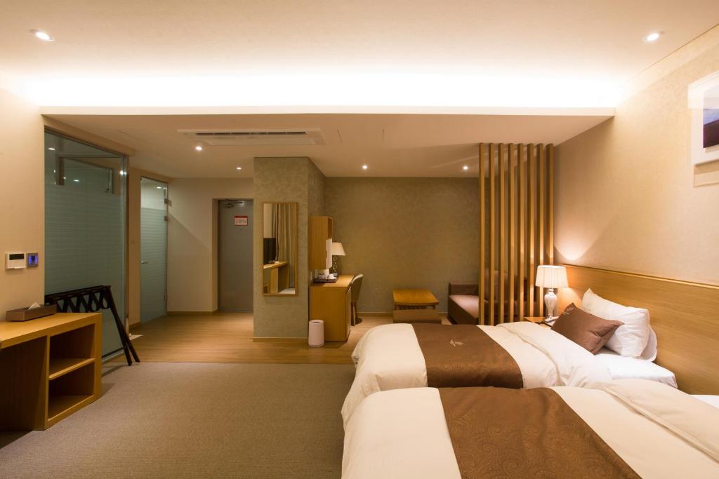 a hotel room with two beds and a desk at Dong Gyeong Hotel in Tongyeong