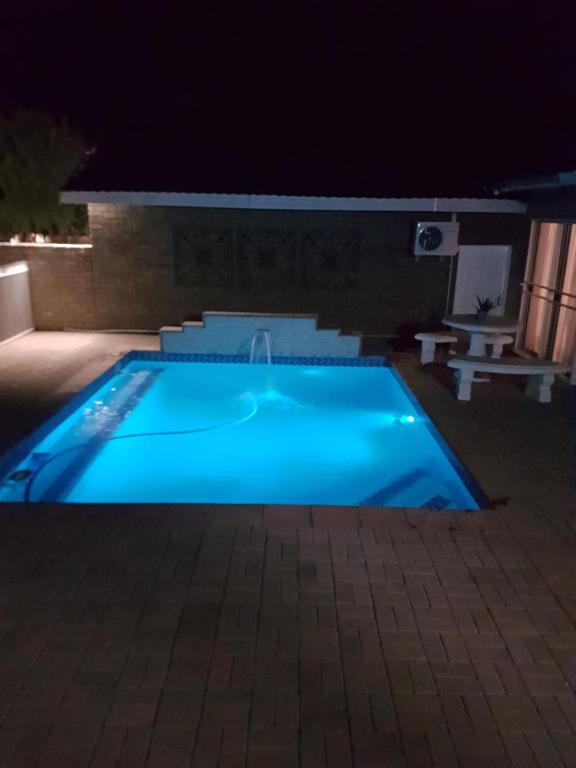 a large blue swimming pool at night at @Home Guest House in Zeerust