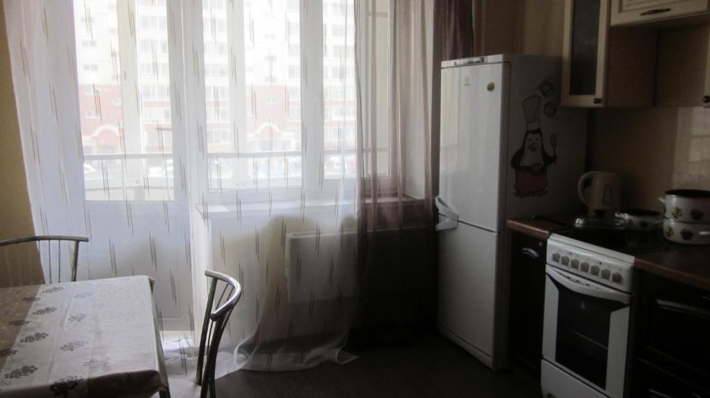 トムスクにあるApartment on Michurinaのキッチン(冷蔵庫、テーブル付)、窓が備わります。