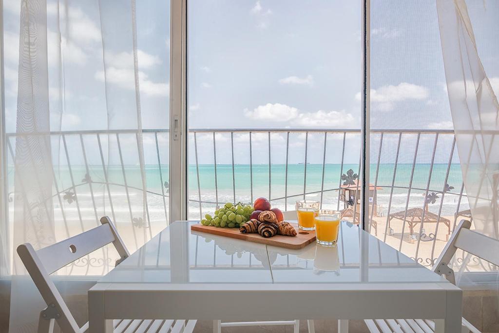 een tafel met een schaal fruit en twee glazen sinaasappelsap bij Dream On the Beach in Haifa