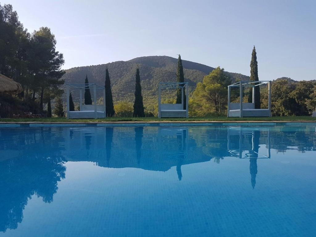 uma piscina de água com árvores e uma montanha ao fundo em Mas del Sord 1335 em La Selva del Camp