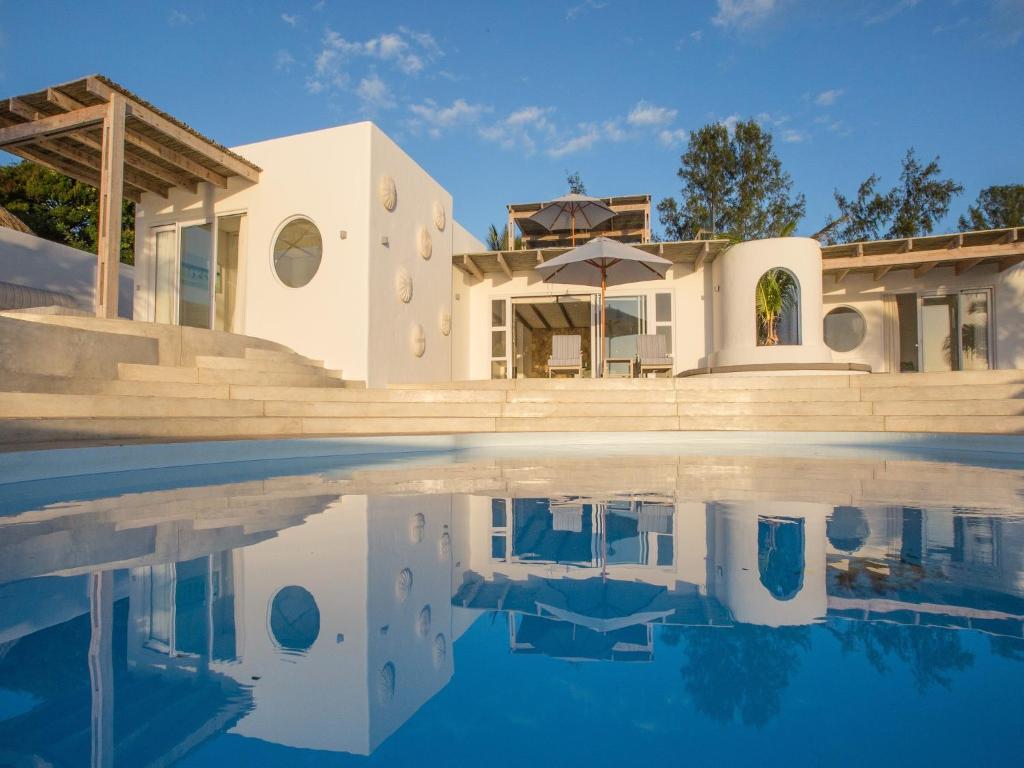 a house with a swimming pool in front of it at Bahia Mar Beach House in Vilanculos