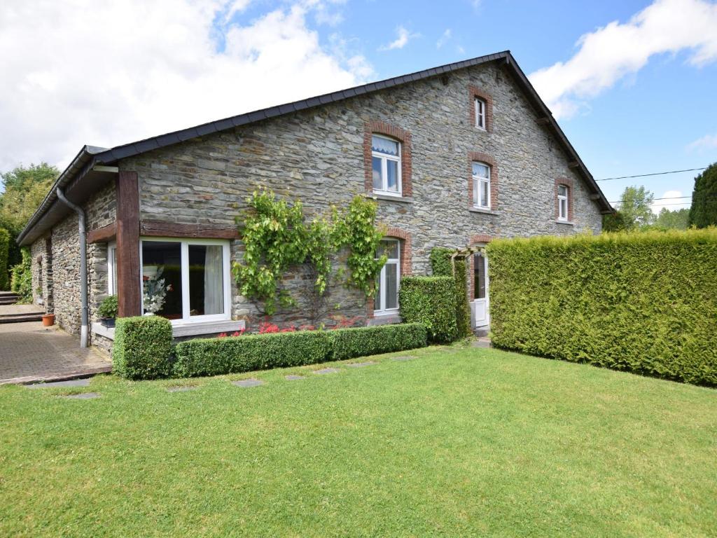 een stenen huis met een groene tuin ervoor bij An old farmhouse in a peaceful Ardennes village in Jehonville