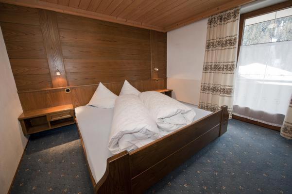 a bedroom with a large bed with a wooden wall at Charlys Ferienwohnung in Samnaun