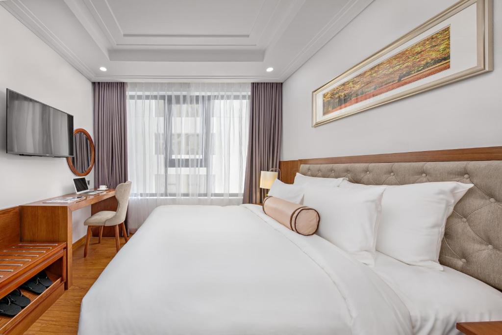 a hotel room with a large bed and a desk at Paris Deli Danang Beach Hotel in Danang