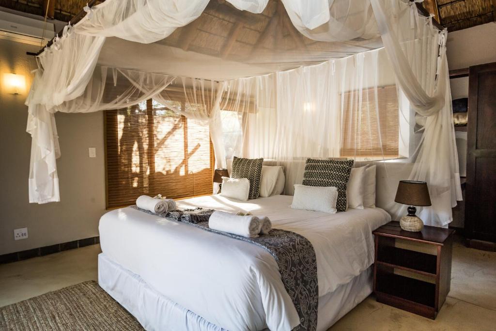 a bedroom with a white bed with a canopy at Raptors Lodge in Hoedspruit