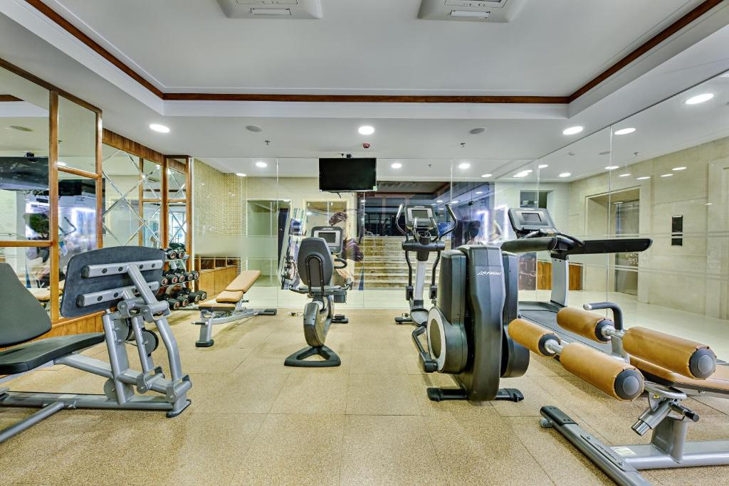 A mirrored fitness room with cardio machines, weights and resistance equipment.