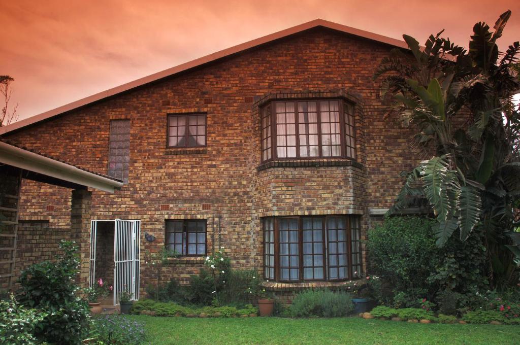 a brick house with windows and a tree at Fig Tree Manor Self Catering in Blythedale