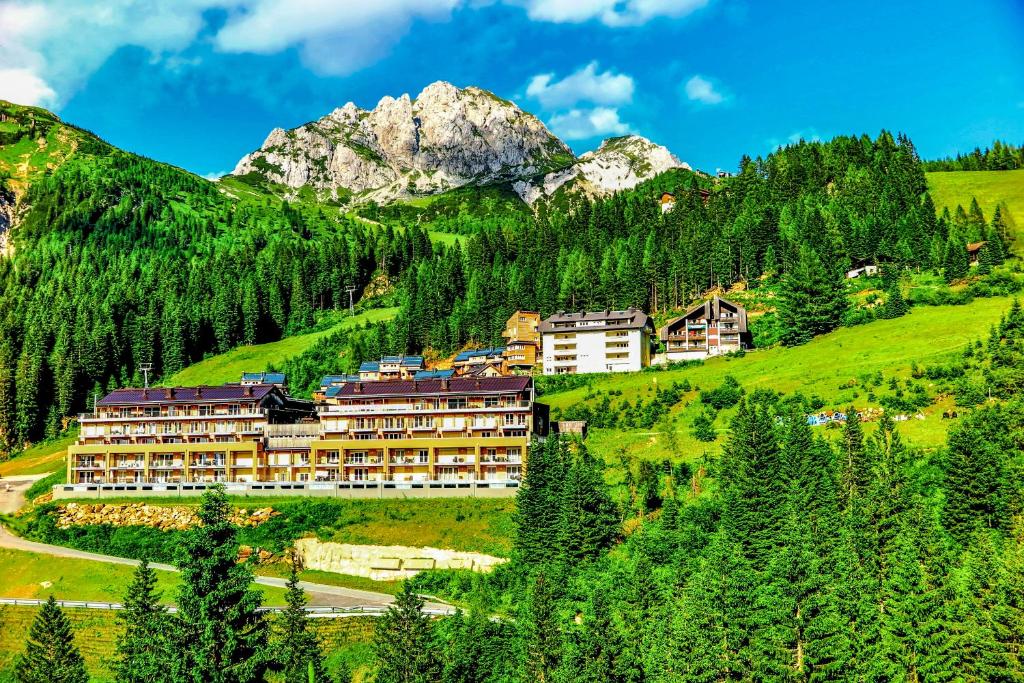 ein Hotel auf einem Hügel mit Bergen im Hintergrund in der Unterkunft Apartments Bergblick in Sonnenalpe Nassfeld