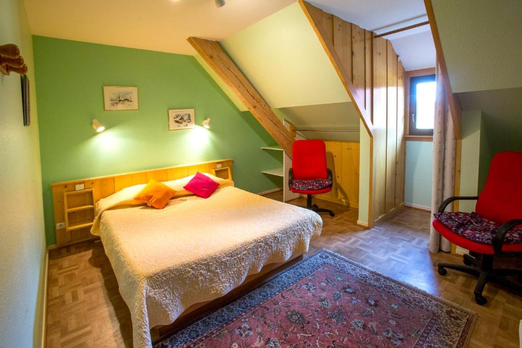 - une chambre avec un lit et deux chaises rouges dans l'établissement Gites Les Cépages, à Ammerschwihr