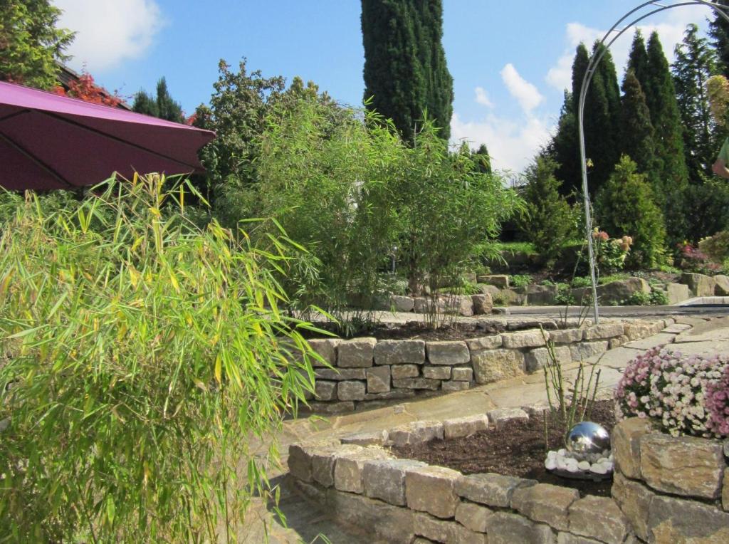 un jardín con una pared de piedra y un jardín con plantas en Ferienwohnung Bambusgarten, en Mössingen