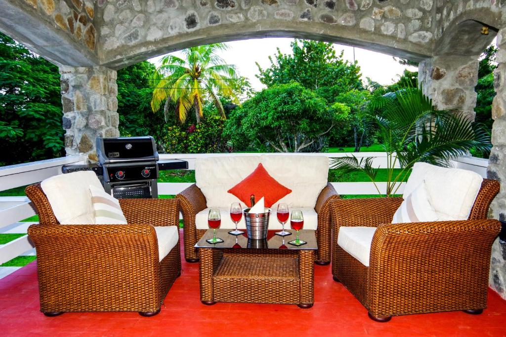 patio z wiklinowymi krzesłami i stołem z kieliszkami wina w obiekcie One Hamilton Place - Emerald w mieście Choiseul