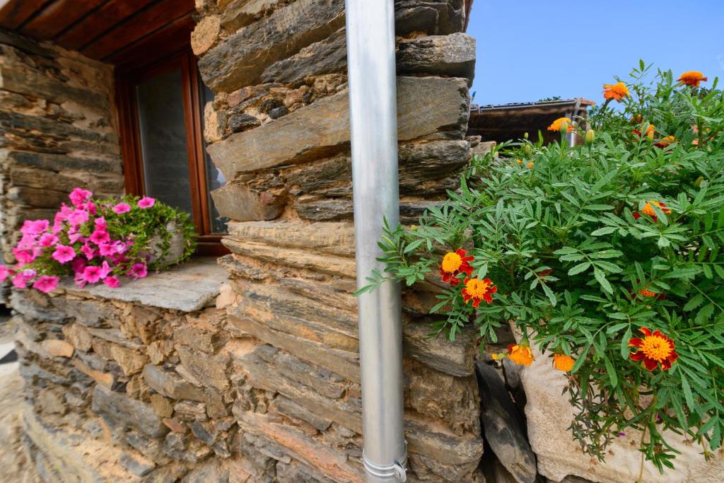 een stenen muur met bloemen en een raam bij Casa do Conto in Doade